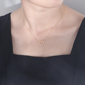 Interlocked double heart necklace in gold with sparkling crystals on model's neck
