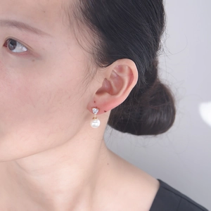 Detailansicht von Herz-Zirkonia und Perlenohrring an einem weiblichen Model