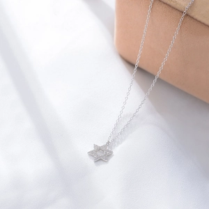 Macro detail of S925 silver hexagram pendant with pave-set zircons on silk background