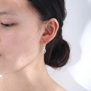 Close-up of gold fishbone drop earrings with sparkling cubic zirconia pavé setting