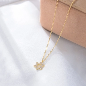 Detailed view of gold S925 silver hexagram pendant with micro-set zircon on pink velvet