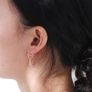 Close-up of gold fishbone hoop earrings with shimmering diamonds on model