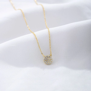 Detailed close-up of a gold pave round pendant necklace on white satin fabric