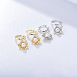Detail of shell-shaped pearl earrings in gold and silver finish with crystal accents