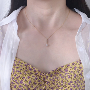 Detail showing a gold pearl pendant necklace with zircon tassel on a woman neck
