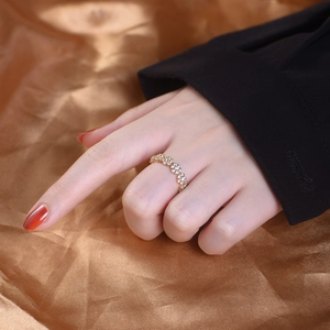 Bague fleurs dorées avec zircons portée au doigt sur fond de tissu satiné