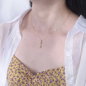 Detail of s925 silver gold pearl tassel necklace worn on neck with floral outfit