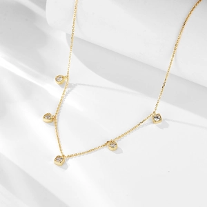 Collier doré minimaliste avec cinq pendentifs en zircon étincelants sur fond texturé