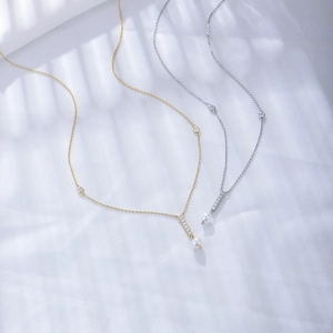 Detailed view of elegant gold and silver pearl necklaces with zircon fringe on white fabric