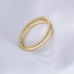 Détail macro d'une bague double en argent S925 plaqué or avec zircon blanc entrelacé