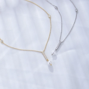 Detailed close-up of geometric tassel pendants with zircons and pearls on blue silk