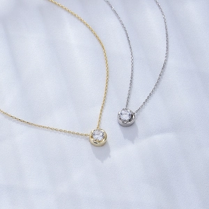 Close-up of gold and silver 925 sterling silver necklaces with round zircon on satin