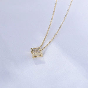 Detail of a square gold necklace pendant with nine embedded sparkling zircon stones