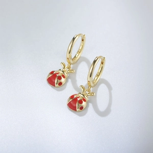 Détail de créoles en argent S925 avec pendentifs coccinelle en émail rouge poli