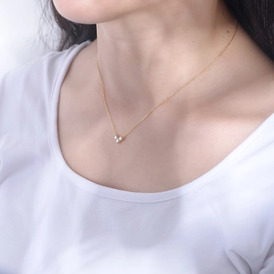 Detail of elegant gold heart pendant necklace with three sparkling clear stones on a model