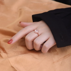 Close-up of square pink quartz ring in rose gold finish worn on a finger over silk