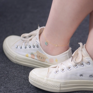 Detailed view of a gold daisy anklet with light blue floral and crystal cross charms