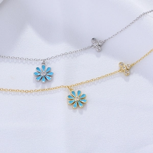 Minimalist silver and gold daisy anklets with blue enamel charms on white silk