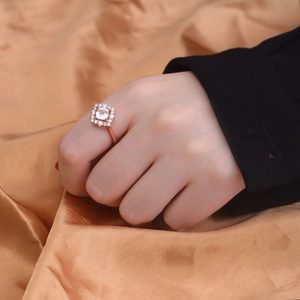 Close-up of a rose gold ring with a cushion-cut pink crystal and diamond halo on model