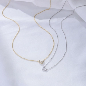 Detailed view of silver and gold heart necklaces with sparkling cubic zirconia on fabric