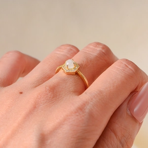 Close-up of gold moonstone ring on hand with hexagon halo and beaded band details