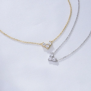 Detail of silver and gold necklaces with three zircon stones in a V-shaped cluster design