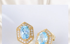 Macro shot of geometric gold earrings featuring oval blue topaz and white zircon halo