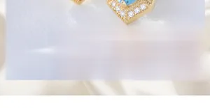 Macro shot of natural blue topaz stud earrings with sparkling halo and gold base