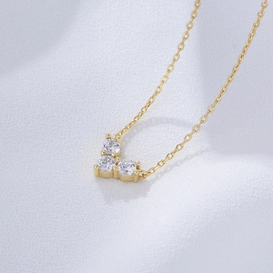 Macro view of gold V-shaped necklace featuring three prong-set round zirconia stones