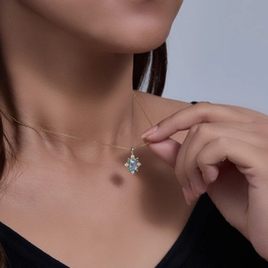 Macro detail of sky blue topaz pendant with vintage gold plating on female model