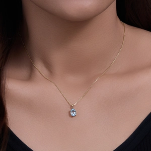 Sky blue topaz sterling silver necklace worn by a model with a gold-tone oval pendant