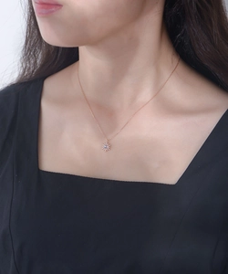 Détail macro d'un collier tournesol en or rose avec opale sur un mannequin femme