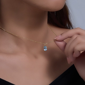 Close-up of a silver sky blue topaz pendant necklace on a woman's neck for elegant look