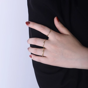 Detailed view of three minimalist gold stackable rings with blue, white and green stones