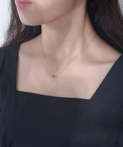 Close-up of a rectangular purple amethyst pendant on a fine gold chain worn by a model