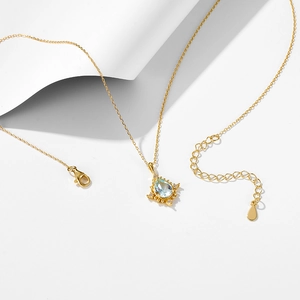 Macro detail of teardrop blue topaz pendant with lobster clasp and adjustable gold chain