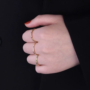 Close-up of three minimalist gold rings set with colorful zircons on a hand