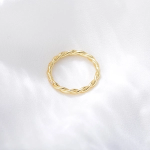 Détail d'une bague torsadée en or avec micro-zircons sur un élégant tissu en soie blanche