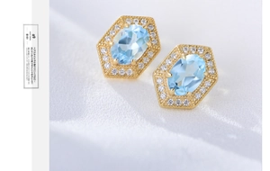 Macro detail of geometric hexagonal stud earrings with blue topaz and diamond halo