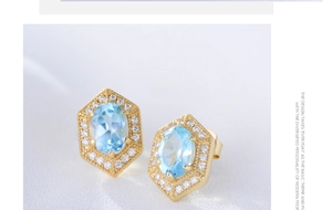 Macro view of geometric gold earrings with oval blue topaz and white zircon halo