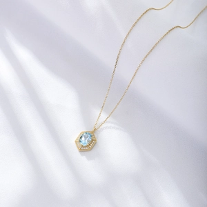 Nahaufnahme eines himmelblauen Topas-Anhängers mit Diamanthalo auf goldener Kette