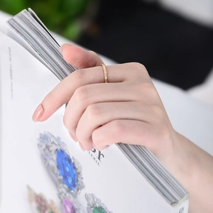 Close-up of minimalist gold zircon ring worn by a model holding a magazine