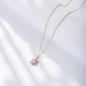 Collier tournesol en or rose avec pierre de lune sur fond élégant en soie blanche