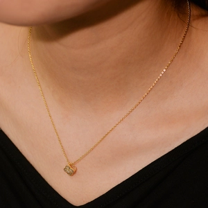 Detailed view of s925 silver four-leaf clover pendant with diamonds on a gold chain