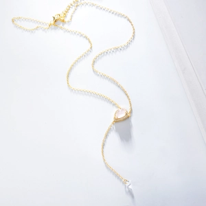 Détail d'un collier en Y doré avec pendentif en quartz rose en poire et petits diamants