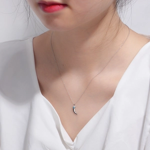 Detail of silver crescent moon necklace with turquoise stone worn on the collarbone
