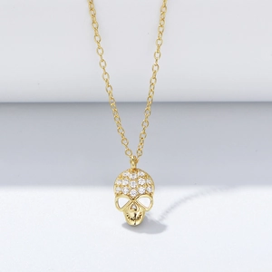 Detailed macro view of gold-tone skull pendant necklace encrusted with sparkling zircons