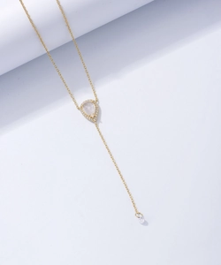 Détail du collier en Y doré avec pendentif goutte en pierre de lune et pompon en zircon