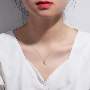 Detail of bohemian gold horn necklace with turquoise and pavé zircons on a model