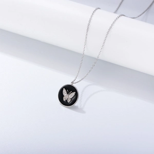 Macro shot of silver circular butterfly pendant with black enamel and sparkling diamonds